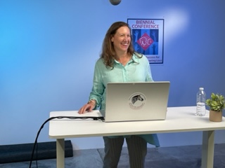 Brenda at her computer behind a table smiling.